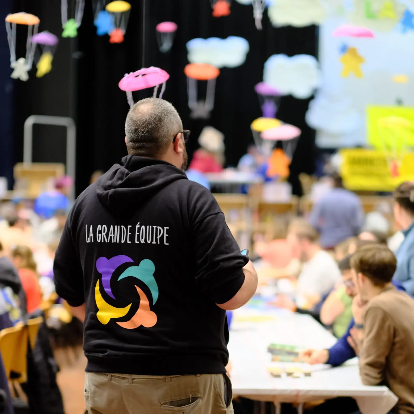 Un bénévole de la Grande Équipe, de dos, dans la salle du festival.