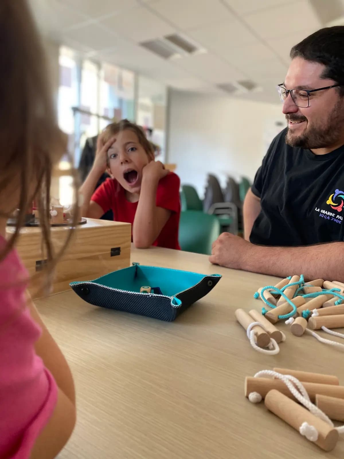 Une enfant fait une grimace de surprise pendant une partie avec un bénévole.